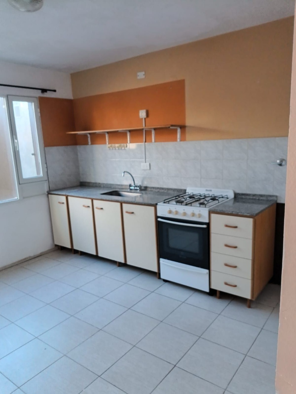 Cocina con mesada de granito, bajomesadas blancas y cocina a gas